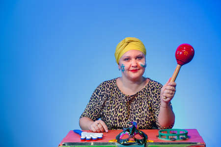 A Jewish woman in a headdress with a painted Magen David face leads the noise on Purim while reading the scroll with a round rattle on a blue background. horizontal photoの写真素材