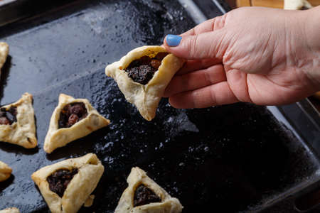A woman's hand takes gomentashi from a baking sheet for the Purim holiday. horizontal photoの写真素材