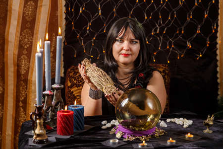 Fortune teller brunette woman in a magical salon is engaged in magic with herbs. horizontal photoの写真素材