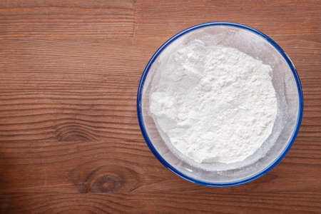 Confectionery flour in a bowl on a wooden table. horizontal photo