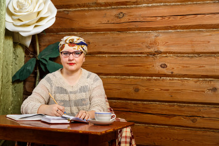 A woman in a turban and glasses at home preparing for a seminar on books picks up material. horizontal photoの写真素材