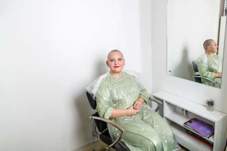 Smiling shaved bald woman in a hairdresser's chair. horizontal photoの写真素材
