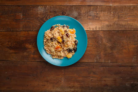 A large dish of couscous with dried fruits, saffron and nuts on a wooden table. horizontal photo