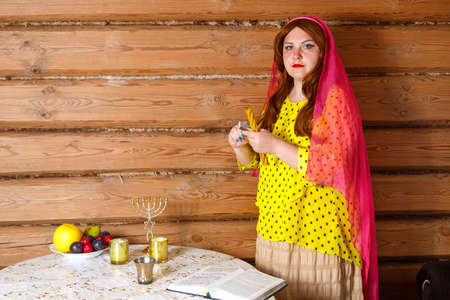 A Jewish woman in a wig and a veil on her head lights the Avdala candle. horizontal photoの写真素材