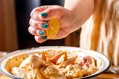 Women's hands squeeze the juice from the lemon on the chicken wings in spices. horizontal photoの写真素材