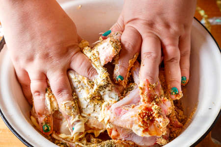 Female hands marinate chicken wings in soy sauce with lemon juice and herbs. horizontal photoの写真素材