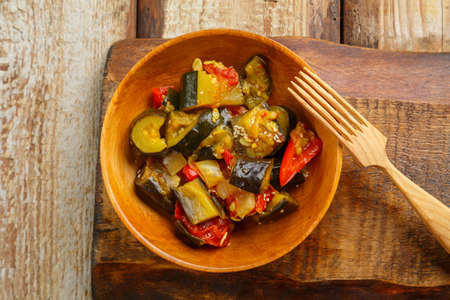 A plate of grilled vegetables on a wooden board next to a wooden fork. horizontal photoの写真素材