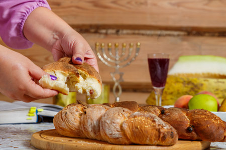 The hands of a Jewish woman break the challah during the Shabbat meal with a blessing. horizontal photoの写真素材