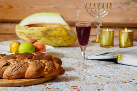 There are two challahs, a glass of wine and fruits on the festive table of Shabbat. horizontal photoの写真素材