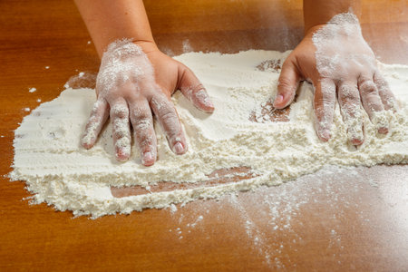 Hands of a Jewish woman on a wooden table in white wheat flour. horizontal photo