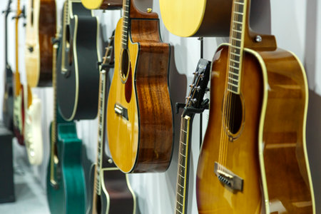 Various guitars of different models hang in the store for sale with a focus on the near guitar....