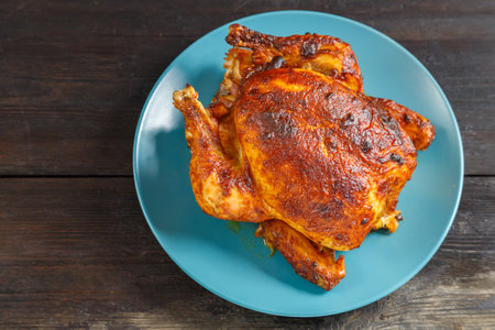 Whole baked chicken carcass with a crust on a platter on a wooden table. save a place. horizontal photoの写真素材