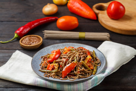Soba with vegetables in soy sauce in a plate on a napkin next to flax seeds and soba. horizontal photoの写真素材