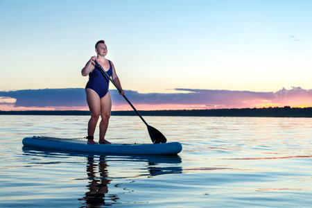 Woman in a swimsuit on a snowboard in the evening at sunset Horizontal photo.