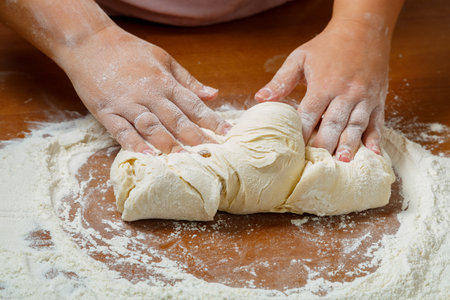 The hands of a Jewish woman knead the dough for wicker challahs for the holiday. horizontal photoの写真素材
