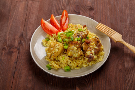 Thai chicken rice garnished with green onions on a wooden table next to a wooden fork. horizontal photoの写真素材