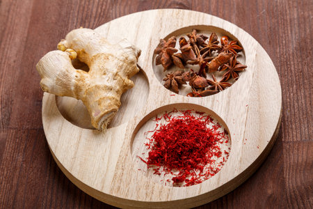 Spices ginger, saffron and anise on a round wooden bowl on the table. horizontal photoの写真素材