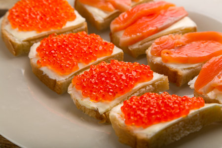 Toasts with red caviar and trout and butter on a plate close-up. horizontal photoの写真素材