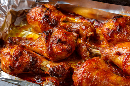 Chicken legs baked in sauce and spices with a crispy crust on foil close-up. horizontal photoの写真素材