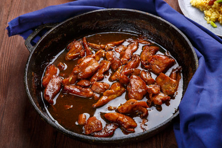 Fried chicken pieces in soy and pad thai sauce in a pan on a blue napkin. horizontal photoの写真素材
