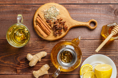 A transparent mug of lemongrass tea on a table next to anise, cinnamon, ginger and honey and a teapot on a wooden board. horizontal photoの写真素材