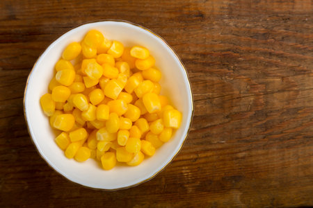 Corn grains in a white plate on a wooden table. save a place. horizontal photo.の写真素材