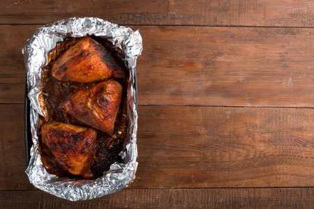 Baked chicken pieces in spices with a crispy crust on foil on a wooden table.copy space..の写真素材