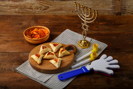 gometashi triangles cookies with mishloach manot jam for Purim laid out on a wooden board on a napkin next to the menorah rattle and whistle. horizontal photoの写真素材