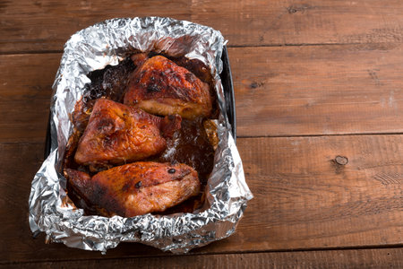 Baked chicken pieces in spices with a crispy crust on foil on a wooden table.copy space.. horizontal photoの写真素材