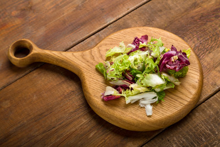 Leaves of green salad mix on a wooden board. horizontal photoの写真素材