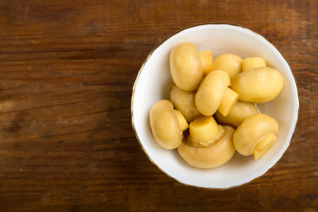 Champignon mushrooms in a white plate on a wooden table. save a place. horizontal photoの写真素材