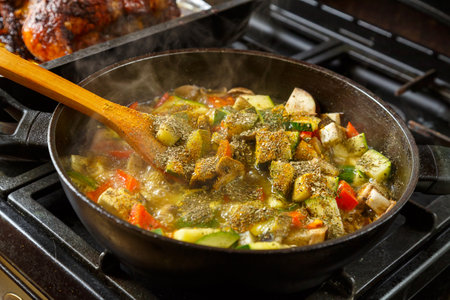 Wooden spoon with stewed vegetables in spices over a frying pan. horizontal photo.の写真素材