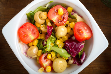 Vegetable salad with champignon corn and cherry tomato with avocado in a white plate. horizontal photo.の写真素材