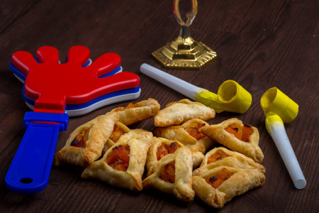 Homemade gomentash cookies for the holiday of Purim on a wooden table next to the rattle. horizontal photo.の写真素材