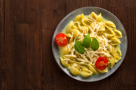 Pasta in cream sauce with cheese garnished with spinach and cherry tomatoes with a fork on a wooden table. horizontal photoの写真素材