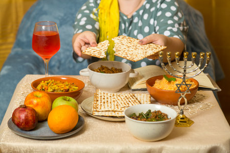 At the festive table, a Jewish woman breaks matzah. horizontal photo