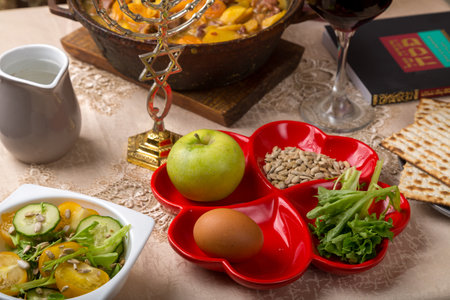 A set table for the Passover Seder with traditional matzah, wine, maror and a hot cholent for the meal. horizontal photo.の写真素材