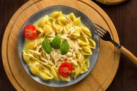 Pasta in cream sauce with cheese garnished with spinach with a fork on a round wooden stand. horizontal photo.の写真素材