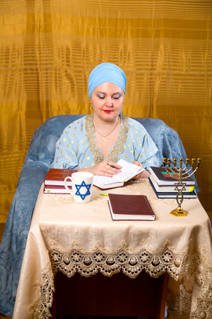 A Jewish woman in a kisui rosh headdress, a teacher of tradition, prepares for classes for women by taking . vertical photo.の写真素材