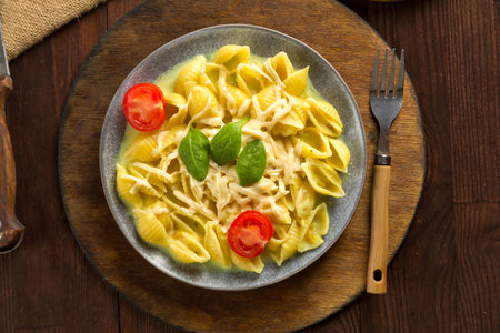 Pasta in cream sauce with cheese garnished with spinach with a fork on a wooden stand. horizontal photo.の写真素材