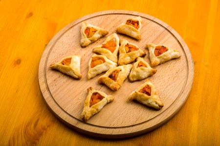 Triangular gomentashi cookies for the Purim holiday on a chalkboard are laid out on a chalkboard on a light table. horizontal photo.の写真素材