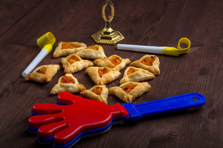 Homemade gomentash cookies for the holiday of Purim on a wooden table next to the rattle. horizontal photo.の写真素材