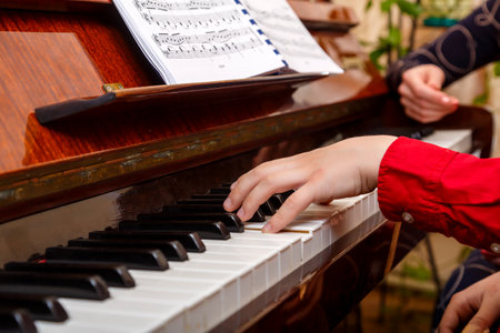 A child learns to play the piano in the lessons at a music school with a teacher. horizontal photoの写真素材