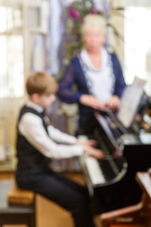 The boy plays the piano under the guidance of a teacher. vertical photoの写真素材