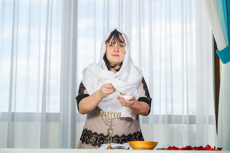 A Jewish woman in a white headscarf performs rituals before the wedding with honey to be desirable for her husband.. Horizontal photo.の写真素材