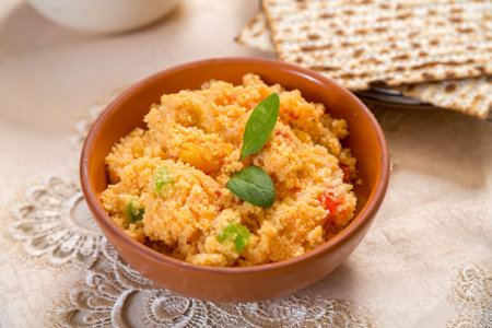 Couscous with dried fruits garnished with herbs in a clay plate on a tablecloth next to a matzah. horizontal photo.の写真素材