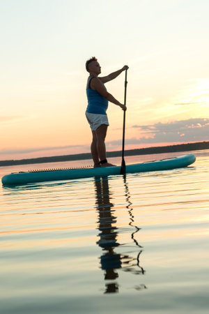A woman floats standing on a sapbod. vertical planの写真素材