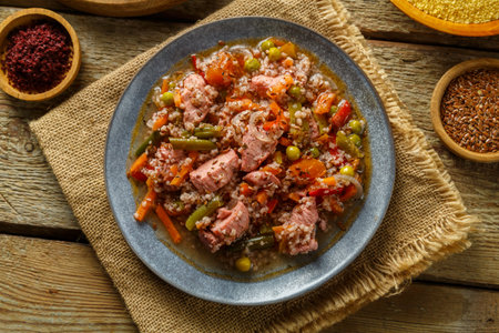 Israeli style couscous with sumac and pieces of stewed chicken on a table on a linen napkin in a plate next to spices Horizontal photoの写真素材
