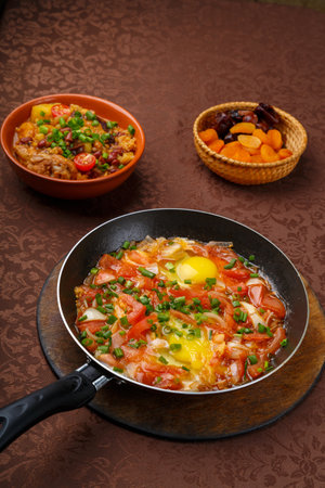 hot shakshuka in a frying pan sprinkled with green onions and chelnt on the sabbath table. vertical photoの写真素材