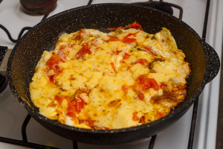Shakshuka with tomatoes and sweet cheese sprinkled in a frying pan on the stoveの写真素材